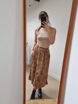 Camel-brown Medi skirt - Medi length skirt in camel-brown/deep beige with a slightly marbled color, which blends nicely and makes it come alive. Wooden buttons for decoration, but not unbuttonable. Elastane in the waistband and belt loops. 100% viscose.  Length: 76 cm 🤎🍁