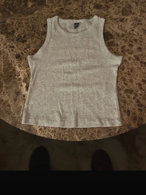 Grå ribbad linnetopp  - Säljer en enkel och stilren grå linnetopp.  Toppen är ribbad och ärmlös med rund halsringning, perfekt att matcha med jeans eller shorts. Materialet är mjukt och stretchigt för en skön passform.