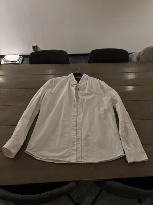 Vit skjorta från Bondelid - Vit skjorta från Bondelid med klassisk krage och knappar hela vägen framtill. Skräddarsydd passform (tailored fit) och långärmad. Materialet är mjuk bomull som känns skönt mot huden. Perfekt för dig som gillar stilrena och tidlösa plagg. Det är bara att skriva om du har några frågor🤗