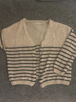 Randig stickad kofta - En beige stickad kofta med svarta ränder från Design By Si, original pris 453kr.