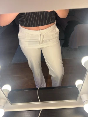 Vita raka byxor med fickor - Säljer ett par vita byxor med raka ben och klassisk passform. 