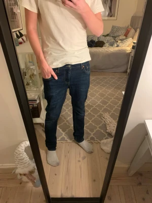 Jeans, Levis 512 - Säljer ett par Levi's 512 Slim Taper jeans i mörkblå tvätt. Modellen har smal passform med avsmalnande ben, klassiska fem fickor och orangea sömmar. Perfekt för dig som gillar en modern och stilren look.