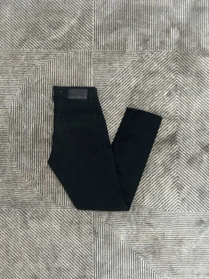 Svarta tiger of Sweden jeans  - Säljer ett par svarta tiger of Sweden jeans med skinny fit och klassisk femficksdesign. Byxorna har hög midja, silverfärgade nitar och svart läderpatch bak i midjan. Materialet är stretchigt jeans för extra komfort och snygg passform.