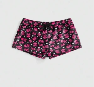 Mjukis-shorts  - Mysiga svarta shorts i fleece med rosa dödskallemönster och små vita hjärtan. De har en söt svart rosett framtill i midjan och en loose passform. Perfekta för chill dagar hemma eller sleepovers.