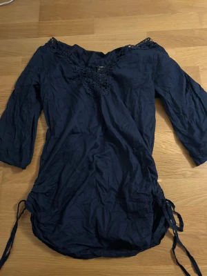 Mörkblå blus - Säljer en mörkblå blus med spets vid kragen och är justeringbar längst ner, jätte skön och luftig, perfekt att ha bikini under och spendera en dag på stranden med den 