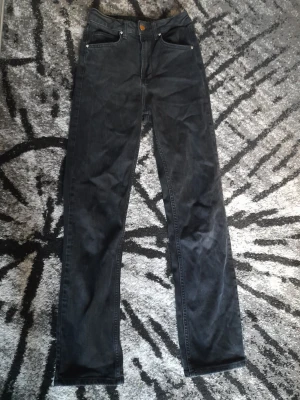 Svarta raka jeans - Säljer ett par svarta jeans med klassisk femficksdesign och raka ben. Jeansen har normal passform och är tillverkade i ett slitstarkt bomullsmaterial. Perfekta till en avslappnad stil och funkar året runt. Storlek waist 26 length 34