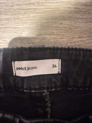 Svarta bootcut jeans från Perfect Jeans - Svarta jeans från Perfect Jeans i storlek 34. Modellen har bootcut-ben och klassisk femficksdesign med snygga fickdetaljer bak. Jeansen är gjorda i ett jeansmaterial med lite stretch för skön passform och sitter snyggt över höften.