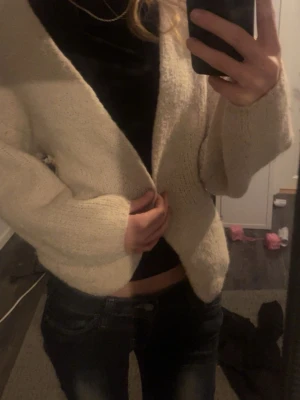 Beige stickad kofta från Lindex - Mysig och enkel beige stickad kofta från Lindex i storlek XS/S. Koftan har långärmade och lite loose passform, perfekt att slänga på sig över en t-shirt eller topp. Den är öppen framtill utan knappar och har en mjuk, stickad känsla.