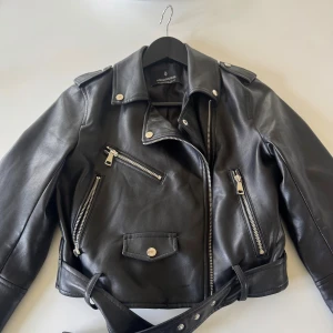 Svart skinnjacka från Stradivarius - Svart skinnjacka från Stradivarius. Modellen är kortare och har långa ärmar. Använd fåtal gånger, nyskick. Nypris 400 kr