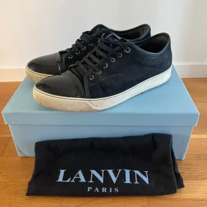 Lanvin skor  - Säljer dessa sjukt snygga Lanvins captoe sneakers i mörkblå färg! Nypris: 4499kr, mitt pris 2200kr. UK10 motsvarar storlek 44! Skick 7/10 sulan börjar bli lite sliten, och captoe har några repor. Box och Dustbag ingår! Hör av dig vid vid minsta fråga eller fundering! 😃