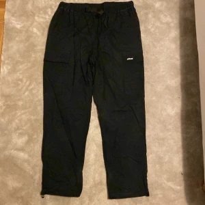 Svarta Stüssy Cargo pants - Skalet är 100% nylon och insidan 100% polyester. Många fickor, ett litet bälte är inkluderat. Är öppen för ett lägre pris vid snabb affär. Om ni har några frågor skriv gärna!