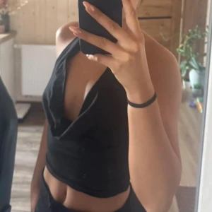 Svart halterneck tubtopp - Säljer en svart halterneck tubtopp med breda band som knäpps i nacken. Toppen har en enkel och stilren design, perfekt att matcha med jeans eller kjol. Mjuk och stretchig bomullskänsla för en bekväm passform. Öppen rygg. Lånad bild