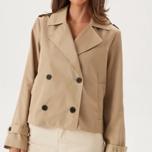 Beige kort trenchcoat  - Säljer denna beiga trenchcoat från Vila. Sparsamt använd och i super fint skick. Storlek 36, passar 34 också. Har några defekter som man kan se på de sista bilderna. Har ett litet hål på bröstet från en majblomma pin, en knapp har gått av på ena axeln och det finns en liten fläck på armen. Fläcken går säkert bort i tvätten. 320 kr + frakt! Vid fler frågor, bilder etc skriv privat 🙌🏼💐✌🏼🩷👍🏼