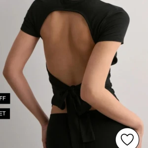 Svart croppad topp med öppen rygg - Snygg svart croppad topp med korta ärmar och öppen rygg som knyts baktill. Tight passform och rund halsringning.