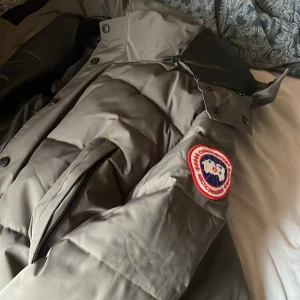Canada goose jacka grå med röd detalj. - En väldigt snygg canada goose som är grå och röd logga. Jackan är väldigt varm och är perfekt till dig som vill ha en helt ny vinter jacka. Den går att scana och allt. Pris kan diskuteras