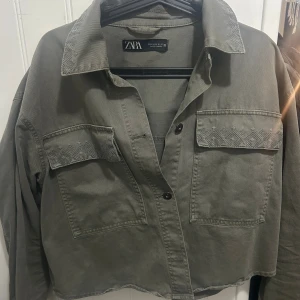 Grå overshirt från Zara med broderi - Snygg grå overshirt från Zara i bomull med broderade detaljer på fickorna och kragen. Jackan har två stora bröstfickor, knappar framtill och en loose passform😇🥰