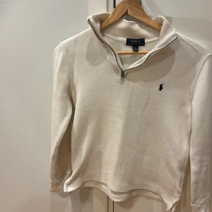 Vit half zip tröja från Polo Ralph Lauren  - Säljer en stilren vit långärmad tröja från Polo Ralph Lauren med half zip i storleken 10-12 . Tröjan har broderad logga på bröstet och är tillverkad i mjuk bomull. Perfekt för lager-på-lager och snygg till jeans eller chinos. Skick är 9/10 som ny mitt pris är 349 kr kom privat vid intresse