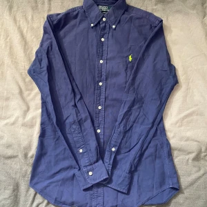 Blå skjorta från Polo Ralph Lauren - Marinblå skjorta från Ralph Lauren i storlek S. Fint skick till ett bra pris. Nypris: 1995kr. Mitt pris: 299kr                  Vid frågor eller funderingar, tveka inte att höra av dig.