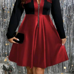 Röd och svart klänning med dragkedja - Snygg röd och svart klänning med långärmade svarta ärmar och dragkedja framtill. Kjolen är i glansigt rött tyg och har en utsvängd form. Perfekt för dig som vill sticka ut med en cool och modern look.