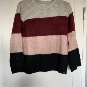 Fin skön  tröja från lager 157 - Mysig stickad tröja från lager 157 med breda ränder i grått, vinrött, ljusrosa och svart. Tröjan har rund halsringning och lång ärm, perfekt för kyliga dagar. Den ribbade strukturen ger en skön och avslappnad vibe. Storlek 160 men passar mig på vanligtvis har xs. Jättefint skick, endast lite nopprig