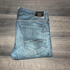 Replay Waitom jeans - Snygga Replay Waitom jeans i blå tvätt med klassiska femficksdetaljer och diskret Replay-logga på bakfickan. Jeansen har en straight passform och raka ben, tillverkade i mjukt denim-material som sitter skönt hela dagen. Midja 43cm, längd 104cm. JAG SKICKAR INGA FLER BILDER NÄR JAG BÄR JEANSEN:)
