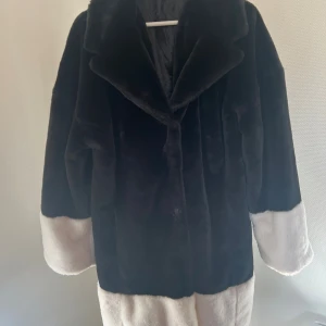 Svart och vit pälsjacka Gina Tricot - Snygg pälsjacka från Gina Tricot i storlek L. Jackan är svart med vita detaljer på ärmslut och nederkant, har bred krage och är helfodrad. Perfekt för dig som vill sticka ut med en trendig och mysig look.