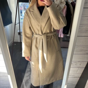 Beige kappa  - Stilren beige kappa från Vero Moda, använd max två gånger så är som ny. 