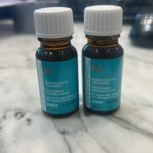 Moroccanoil Treatment Light 10ml - Två små flaskor Moroccanoil Treatment Light, 10 ml vardera. Perfekt för fint eller ljust hår. Kommer i bruna glasflaskor med vita skruvkorkar och turkosa etiketter. Oljan ger glans och mjukhet till håret och är enkel att ta med i väskan. 99kr STYCK 