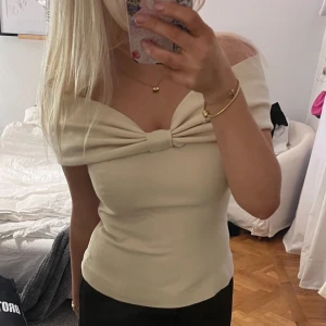 Beige offshoulder topp med rosett - Säljer en krämvit offshoulder topp med snygg rosettdetalj framtill. Från nakd endast använd en gång 🩷