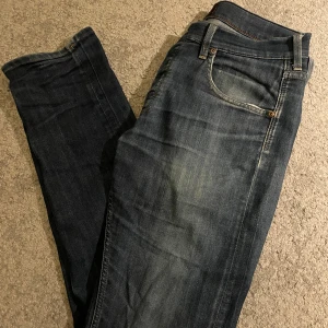 Lee Daren jeans blå - Snygga Lee Daren jeans i klassisk blå tvätt med slitningar och lätt blekta partier. Modellen har raka ben, fem fickor och Lee-logga på bakfickan. Jeansen har orange sömmar och är tillverkade i bomull för en skön känsla.