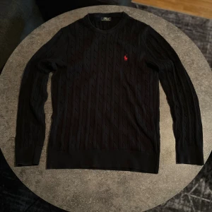 Svart kabelstickad Polo Ralph Lauren tröja - Svart kabelstickad tröja från Polo Ralph Lauren. Den köptes för 2500 kr och är använd endast ett fåtal gånger
