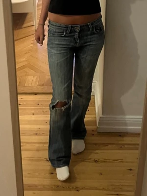 Blå bootcut jeans med slitning - Säljer dessa jätte snygga Lee jeans,då de tyvärr inte kommer till användning! Köpta second hand men har gjort hålet själv, bra skick. Storlek 26/31 på etiketten och passar mig som brukar ha ca 34 i jeans. Skriv för andra frågor!💕