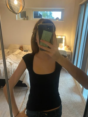 Svart topp med fyrkantig hals Gina Tricot - Säljer en svart topp från Gina Tricot i storlek XS. Toppen har en fyrkantig halsringning och är kortärmad med en tight passform. Super mjuk, skön och stretchig topp som passar till alla outfits. En bra basic att ha som bara används 3 gånger!!