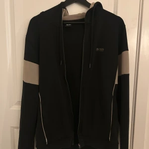 Hugo boss kofta - Svart/Beige Hugo Boss kofta. Har tvättat den en gång och haft på mig den en enstaka gång. Ser helt ny ut.