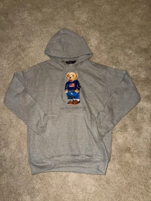Polo Ralph Lauren Polo Bear Hoodie – Grey – Strl M – Äkta - Äkta Polo Ralph Lauren hoodie med klassiska Polo Bear-motivet. Grå färg, storlek M. Mjuk och kraftig kvalitet med borstad insida.  Mycket fint skick – inga fläckar, hål eller slitage. Populär och för ett bra pris. Pris går att diskutera.