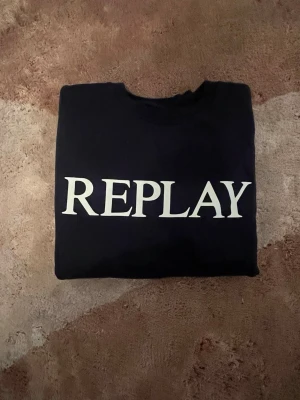 mörkblå sweatshirt från Replay - Säljer en mörkblå sweatshirt från Replay med stor vit logga framtill. Klassisk rund halsringning och långa ärmar. Tillverkad i mjuk bomull för skön känsla. Perfekt till jeans eller joggers för en clean och enkel stil.