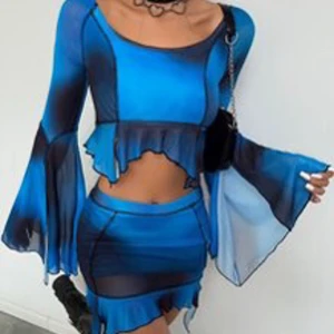 Blå/svart mesh croppad topp och kjol med volang från SHEIN - Säljer en blå och svart mesh topp och kjol med långa utsvängda ärmar och volangdetalj nertill. Toppen är croppad och har en asymmetrisk, edgy look med transparent material. Perfekt för dig som gillar statement-plagg och vill sticka ut. Båda delarna är i storlek L.  Båda delarna är stretchiga.  Nypris 199kr Tyvärr är toppen lite sönder på ryggen (se bilderna)
