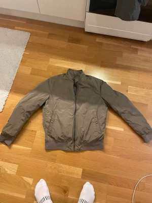 Brun bomberjacka från Massimo Dutti - Snygg brun bomberjacka från Massimo dutti i storlek M. Passar även dig som brukar använda small. Jackan har två fickor med knappstängning och en smidig dragkedja framtill. Materialet är lätt och känns skönt mot kroppen, perfekt för dig som gillar stilrena och enkla plagg.