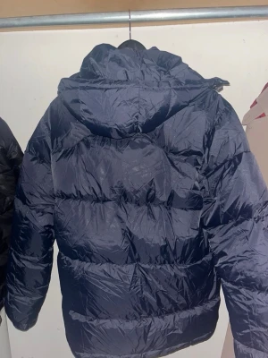 Polo Ralph Lauren jacka  - Snygg mörkblå dunjacka från Polo Ralph Lauren med huva och dragkedja framtill. Jackan har ett broderat rött Polo-logo på bröstet, två sidofickor med dragkedja. En helt ny jacka, säljer den på grund av att den va stor på mig. Priset kan alltid diskuteras 