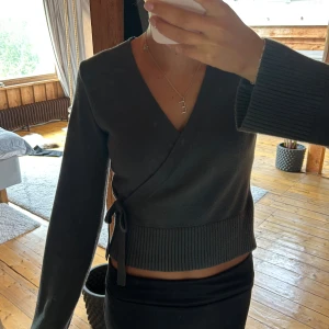 Grön omlottopp  - Snygg mörkgrön omlottopp med v-ringning och långa ärmar. Toppen har ribbad nederkant och knyt i sidan för en extra detalj. Så mjuk och skön stickad känsla💓Använd ca 5 gånger, från Gina Young storlek 158/164 men passar mig som har S