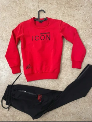 Svarta mjukisbyxor ICON Ibrahimovic - Svarta mjukisbyxor med röd ICON Ibrahimovic-logga på benet. Byxorna har dragsko i midjan, zip-detaljer vid fickorna och är tillverkade i mjukt material som passar chill och sport. Snygg, modern look med slim passform och bekväm känsla.