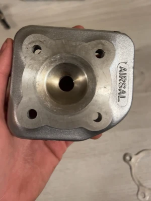 Airsal cylinderkit till moppe - Säljer ett cylinderkit från Airsal till moped, komplett med cylinder, topplock, packning och kolv. Delarna är i metall med en rå silvergrå finish och har en robust, industriell design. Perfekt för dig som vill trimma eller byta ut din moppecylinder.