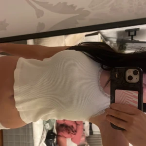 Vit ribbad linnetopp med spets från brandy - Säljer en vit ribbad linnetopp från Brandy storlek S. Toppen är ärmlös och har fina spetsdetaljer runt halsringningen och ärmkanterna. Materialet är mjuk bomull och modellen är slim med en croppad passform. Perfekt för sommarens alla tillfällen!