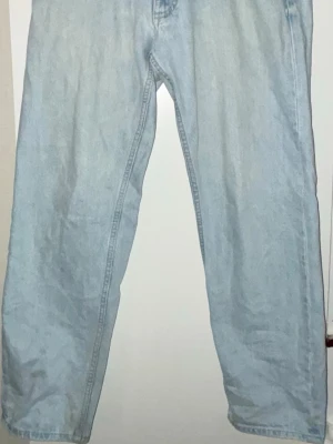 Ljusblå jeans med rak passform - Säljer ett par ljusblå jeans med klassisk rak passform. Jeansen har fem fickor och är tillverkade i ett mjukt denimtyg som ger en avslappnad vibe. Perfekta för dig som gillar en enkel och tidlös stil.