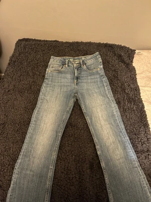 Blå jeans från Lab Industries, strl 152 - Snygga blå jeans från Lab Industries i klassisk femficksmodell. Jeansen har raka ben och normal passform, med ljus tvätt och slitningar för en cool look. Tillverkade i jeansmaterial med detaljerade sömmar och knappstängning framtill.