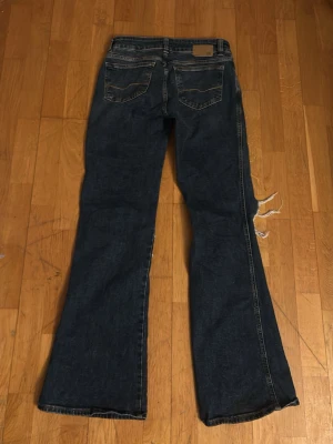 Blå bootcut jeans med hål - Säljer ett par mörkblå bootcut jeans med hål, använda endast enstaka gånger.