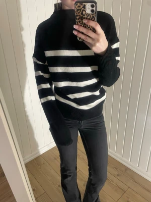 svartvit stickad tröja  - Säljer en svart och vit randig stickad tröja från SHEIN i storlek XS. Tröjan har breda horisontella ränder, hög hals och långa ärmar med ribbade muddar. 