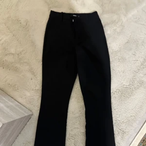 Svarta kostymbyxor från BikBok - Snygga svarta kostymbyxor från BikBok i klassisk rak modell. Byxorna har hällor för bälte, diskreta fickor och stängs med dragkedja och hake. Perfekta till en stilren look och passar till många olika outfits.