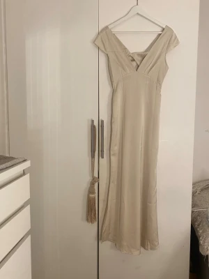 Balklänning  - En gul klänning som upplevs mer som beige med ett lyster. Den är lång i modellen. Storlek S. Endast testad. Aldrig använd