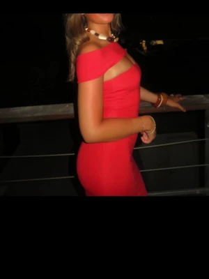 Design by si - Röd offshoulder klänning  - Säljer en snygg röd kortklänning med offshoulder-design och figurnära passform. Klänningen har en djup rygg och breda axelband som ger en cool look. Perfekt för dig som vill sticka ut med en färgstark och trendig outfit.